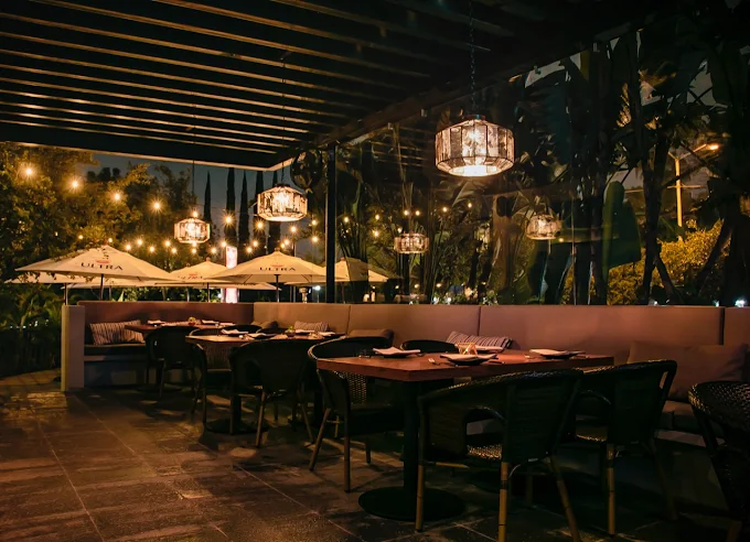 Terraza de noche con candiles colgantes y mesas preparadas